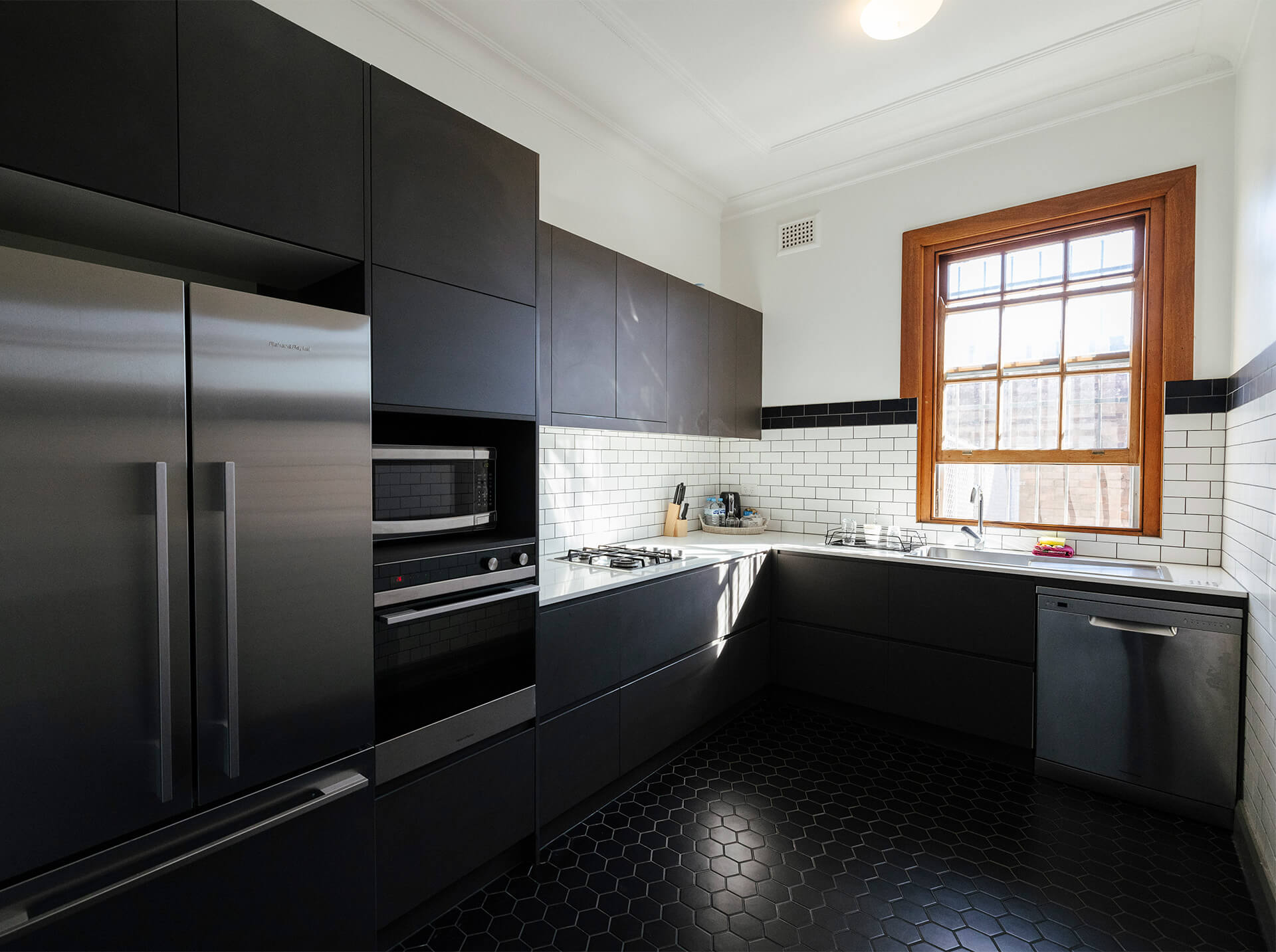 A modern kitchen with sleek black cabinets and shiny stainless steel appliances in a Guildford hotel apartment.