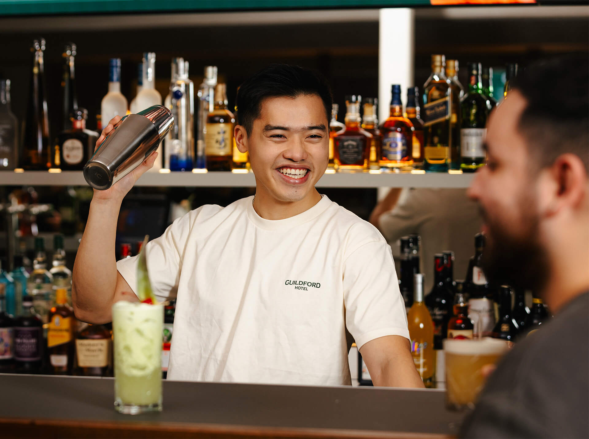 A bartender at Guildford Hotel, smiling while confidently holding a cocktail shaker. Cheers to a great time!