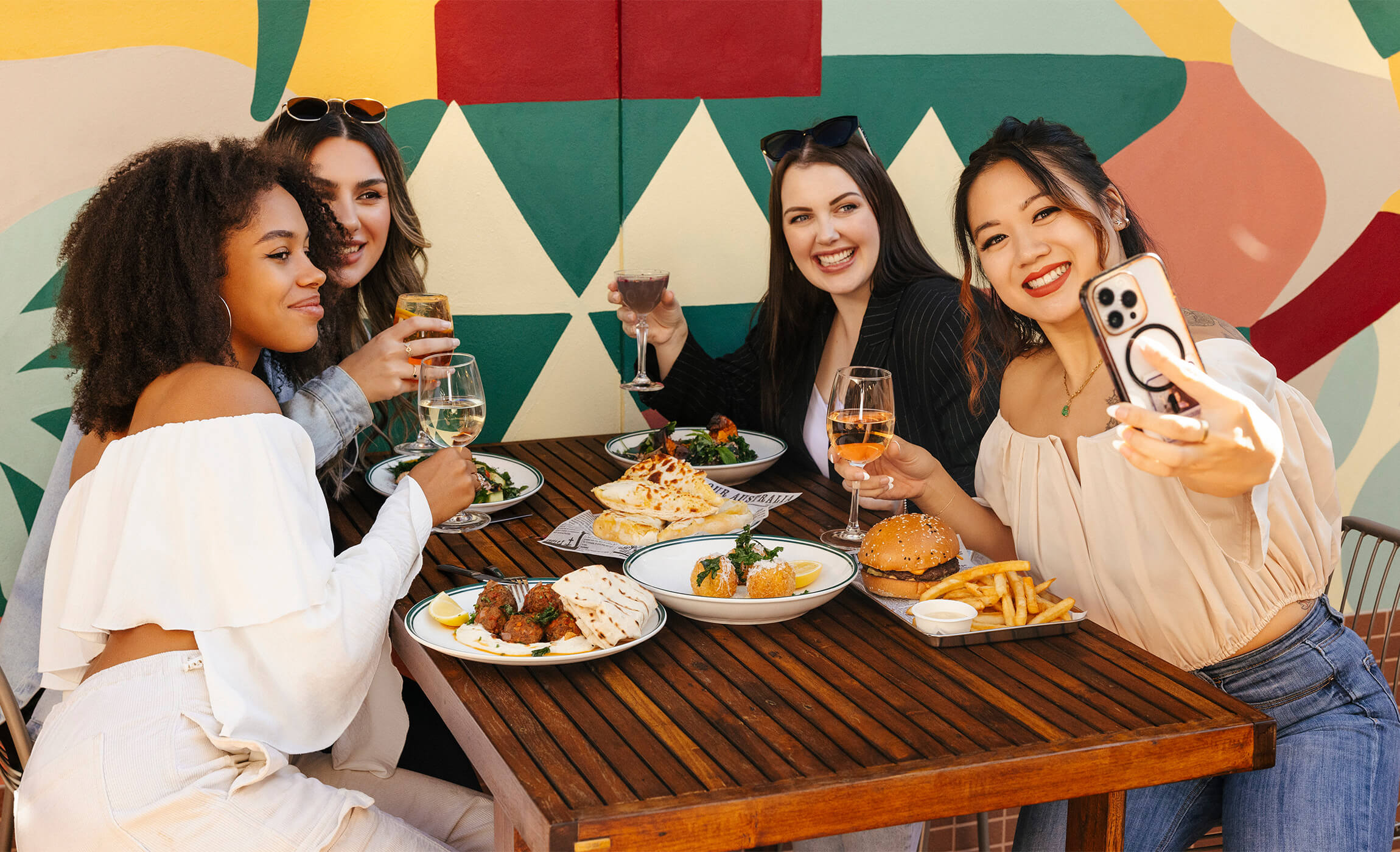 Four women enjoying a meal together at a restaurant, sharing laughter and good times.