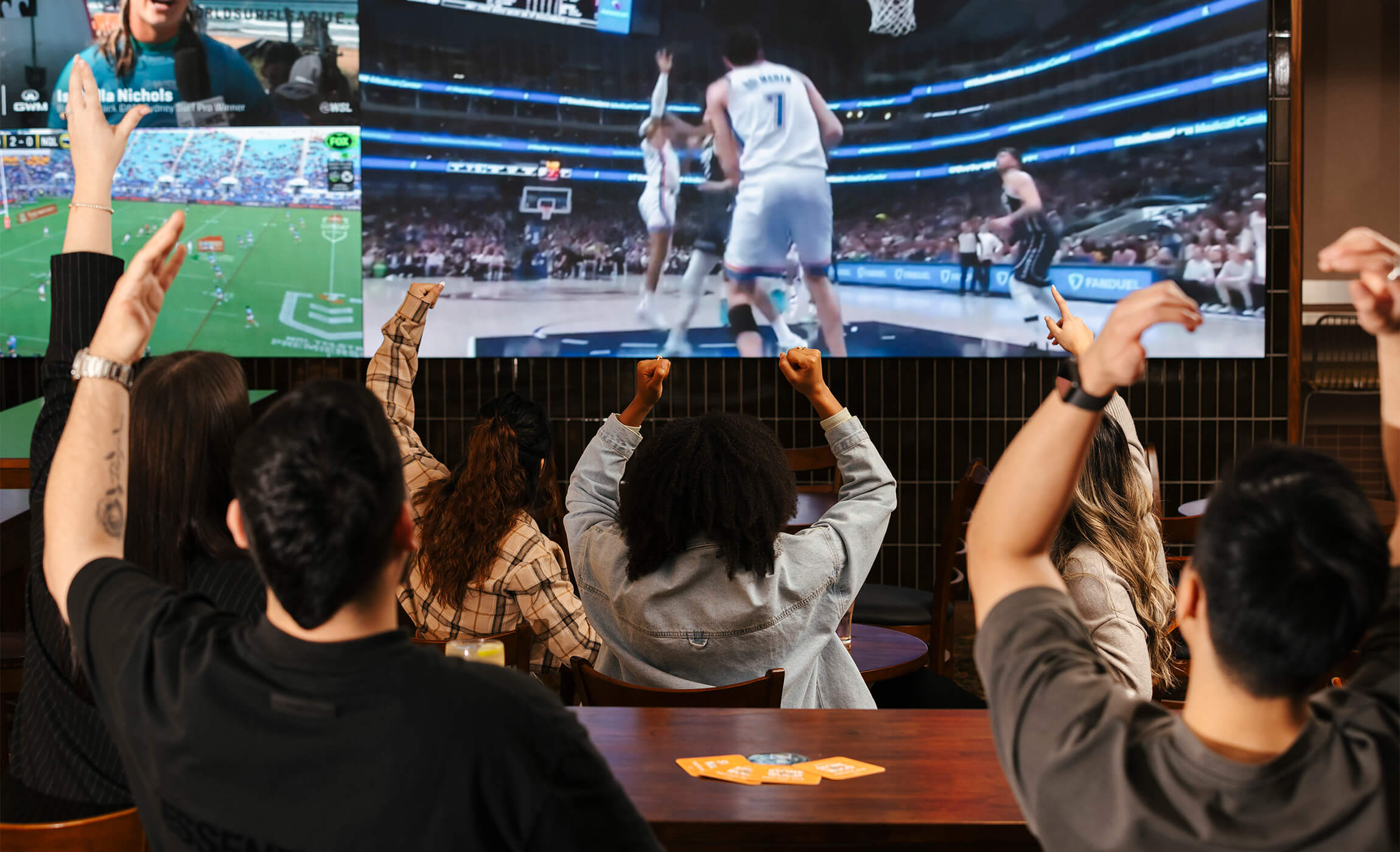 A lively crowd gathered around a TV, engrossed in a basketball game. Excitement fills the air as everyone cheers for their favorite team.