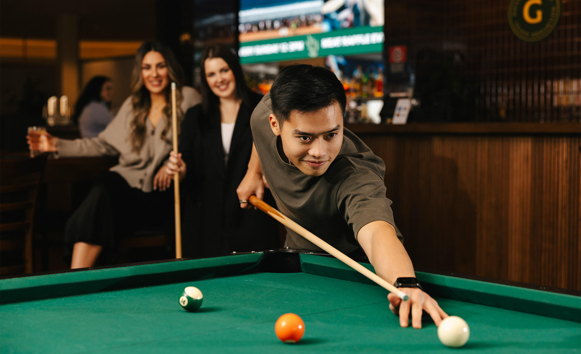 A group of young friends having a great time playing pool in a lively bar.